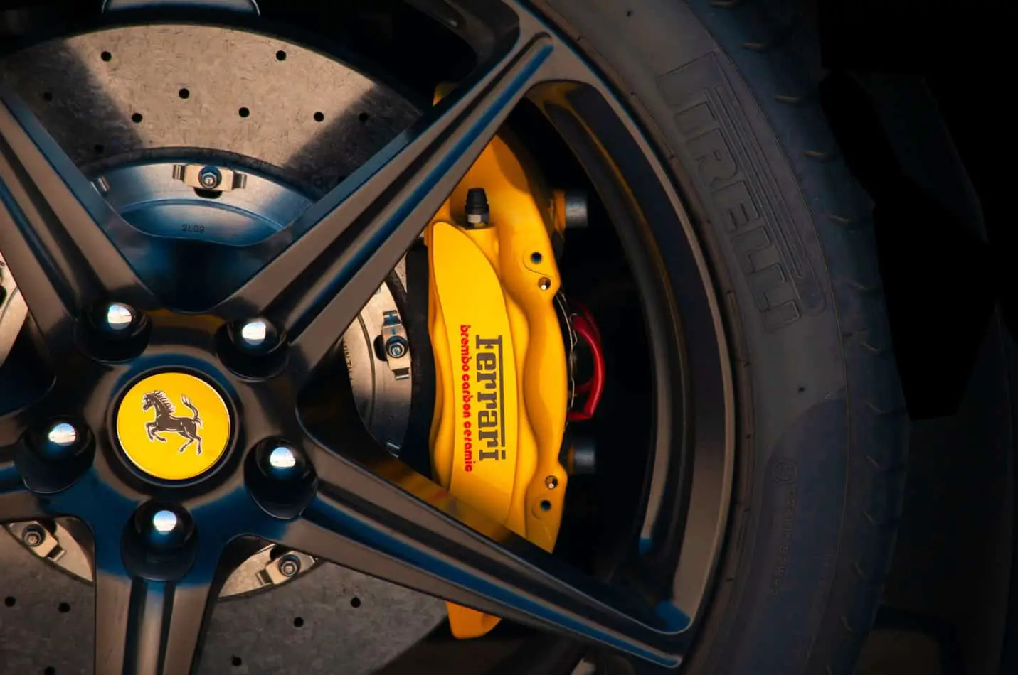 Yellow Ferrari brake calipers on brakes seen through black 5 spoke Ferrari rims